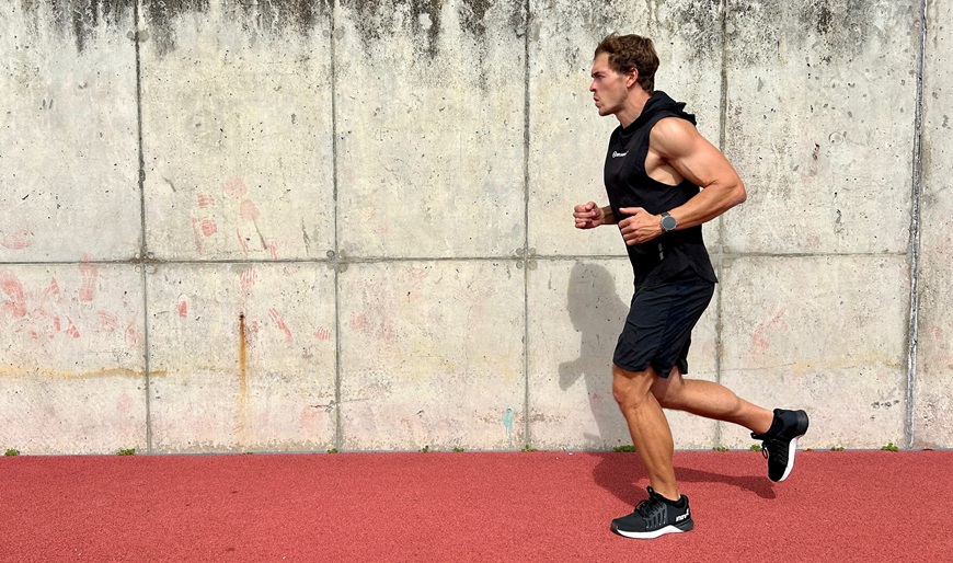 Muž v športovom outfite bežiaci po atletickej dráhe s inteligentnými hodinkami Garmin fēnix® 9 Pro na zápästí