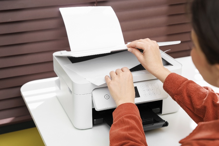 Ako vybrať tlačiareň? Žena vkladá do tlačiarne papier na kopírovanie.