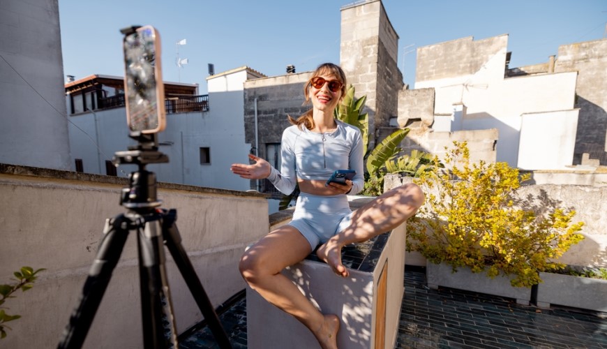 Jak vybrat stativ na mobil, fotoaparát či kameru? Žena natáča videá na mobilný telefón so statívom.