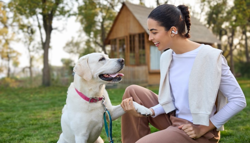 Shokz OpenDots 2 a OpenDots Air: Otvorené slúchadlá, ktoré vás neodstrihnú od okolia Žena sa hrá so psom a má slúchadlá Shokz OpenDots 2