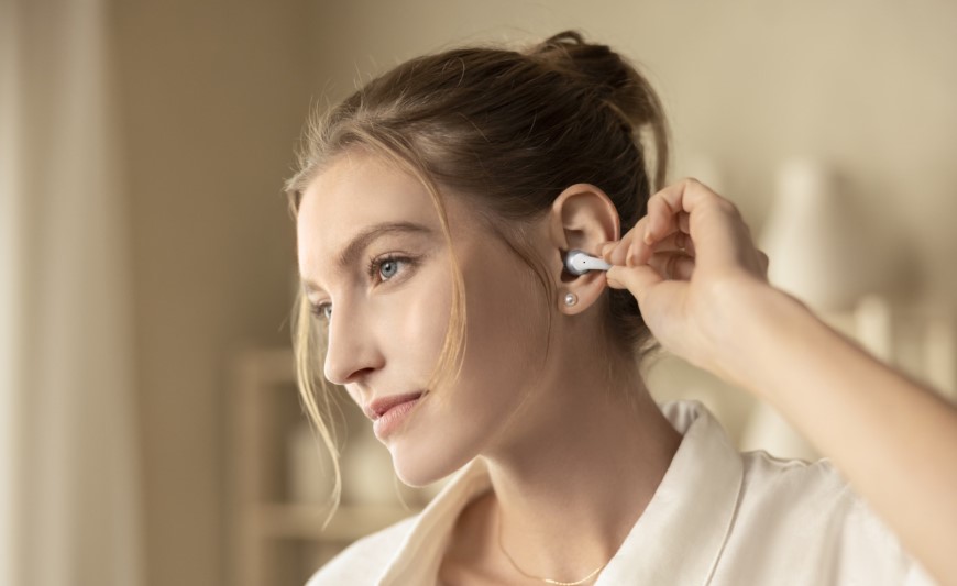 Shokz OpenDots 2 a OpenDots Air: Otvorené slúchadlá, ktoré vás neodstrihnú od okolia Žena si nasadzuje otvorené slúchadlo OpenDots 2 Shokz