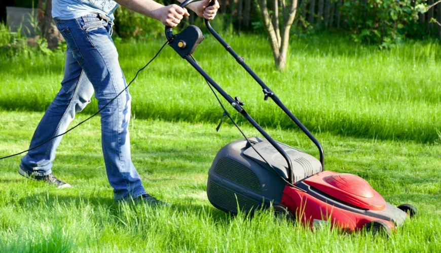 Ako vybrať kosačku Muž kosí trávu elektrickou kosačkou