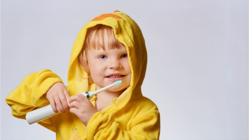 Ako vybrať elektrickú zubnú kefku? dieťa si čistí zuby elektrickou zubnou kefkou