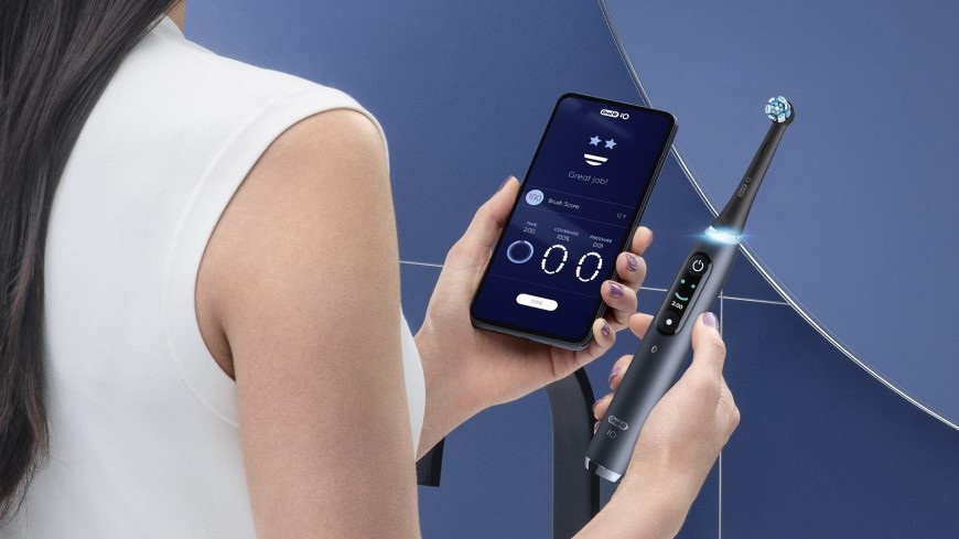 Ako vybrať elektrickú zubnú kefku? žena drží v ruke mobil, na ktorom má spustenú aplikáciu na čsutenie zubov pre zubnú kefku Oral-B iOTM