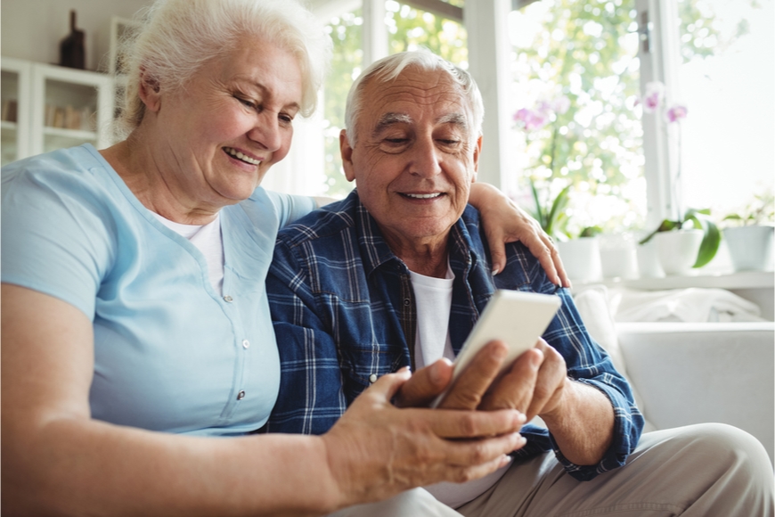 Najlepšie mobily pre seniorov Starší pár sedí na pohovke a prezerá si niečo na mobilnom telefóne.