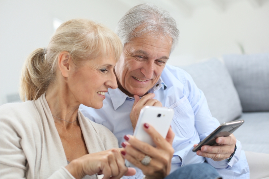 Najlepšie mobily pre seniorov Starší pár si ukazuje vzájomne niečo na displejoch svojich telefónov.