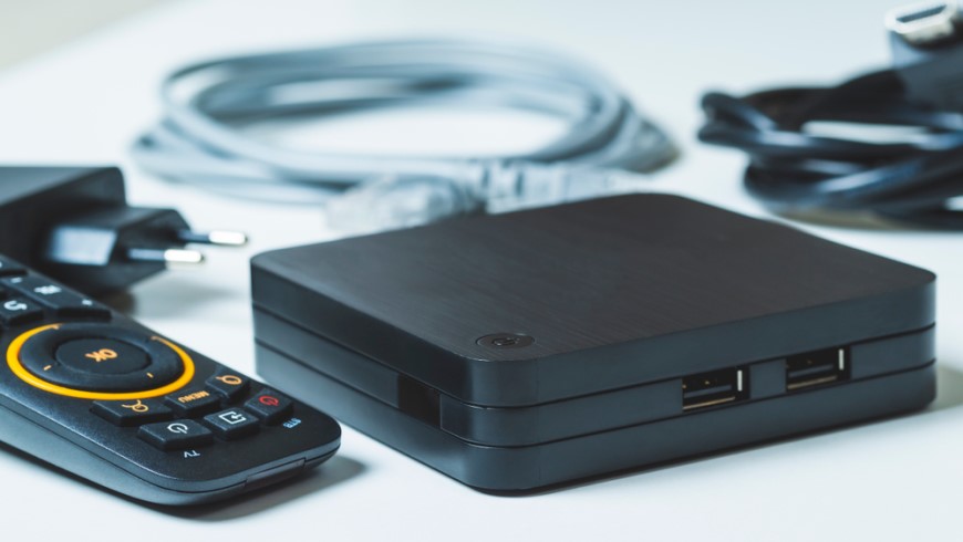 Ako bojovať so zlým signálom televízora? detailný pohľad na set-top box s diaľkovým ovládaním na pozadí s rozostrenými káblami