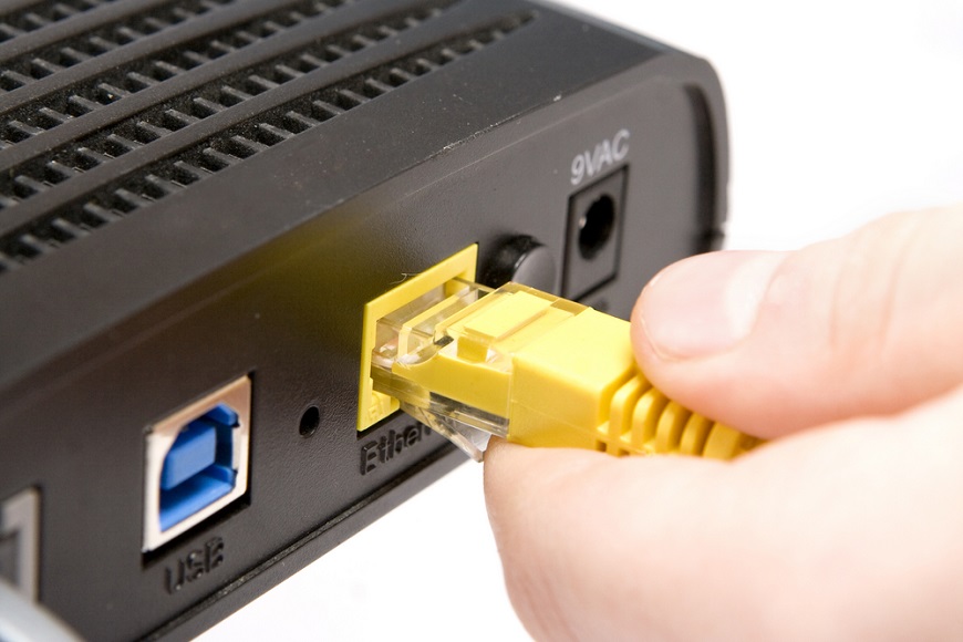 detailný pohľad na zapájanie žltého ethernet kábla do ethernet konektora na zadnej strane routera