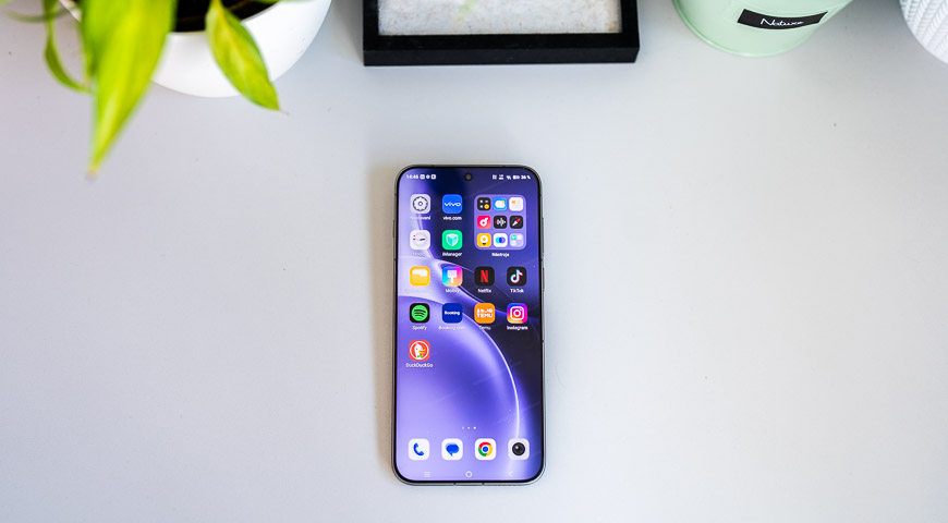 Recenzia: vivo X300 Pro – S kráľom zoomu určite nešliapnete vedľa Smartfón vivo X300 Pro s rozsvieteným displejom na stole, zobrazujúci domovskú stránku s aplikáciami, v hornej časti vidieť časti rastlín
