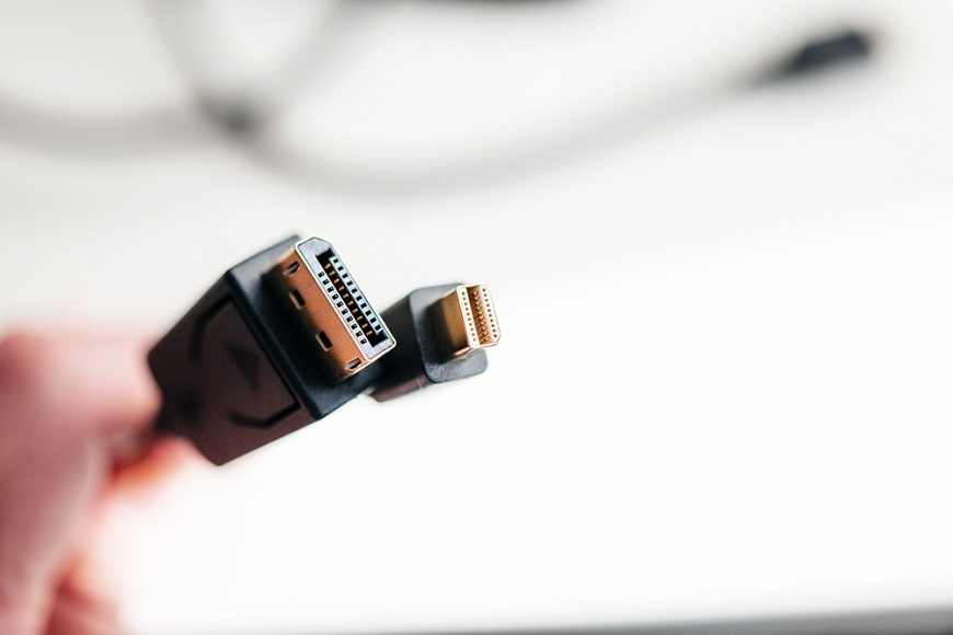 Ako pripojiť monitor k notebooku? detailný pohľad na display port; prsty, ktoré ho držia sú rozostrené