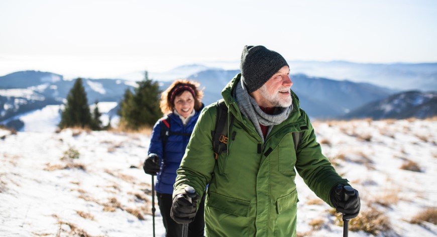 muž so ženou sú na túre v zasnežených horách v outdoorovom oblečení