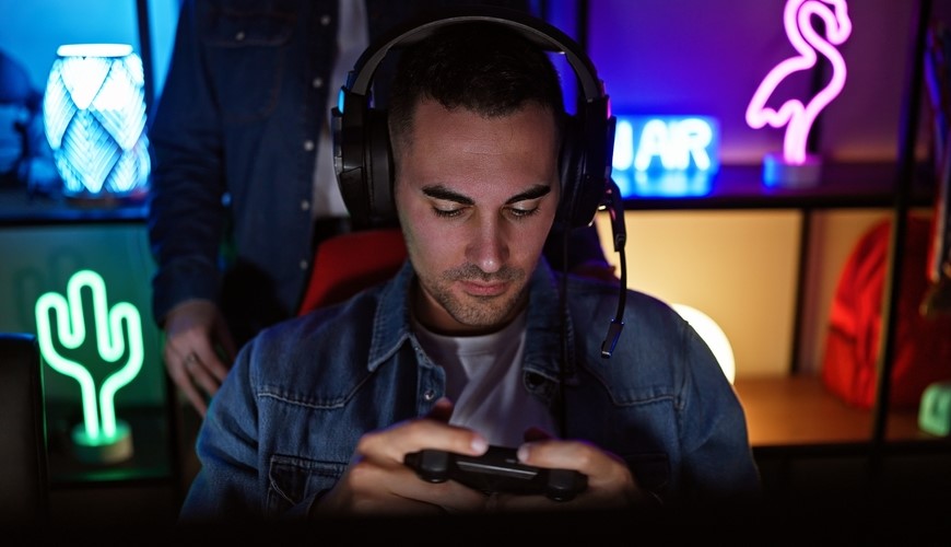 Ako pripojiť bezdrôtové slúchadlá? Muž so slúchadlami hrá hru.