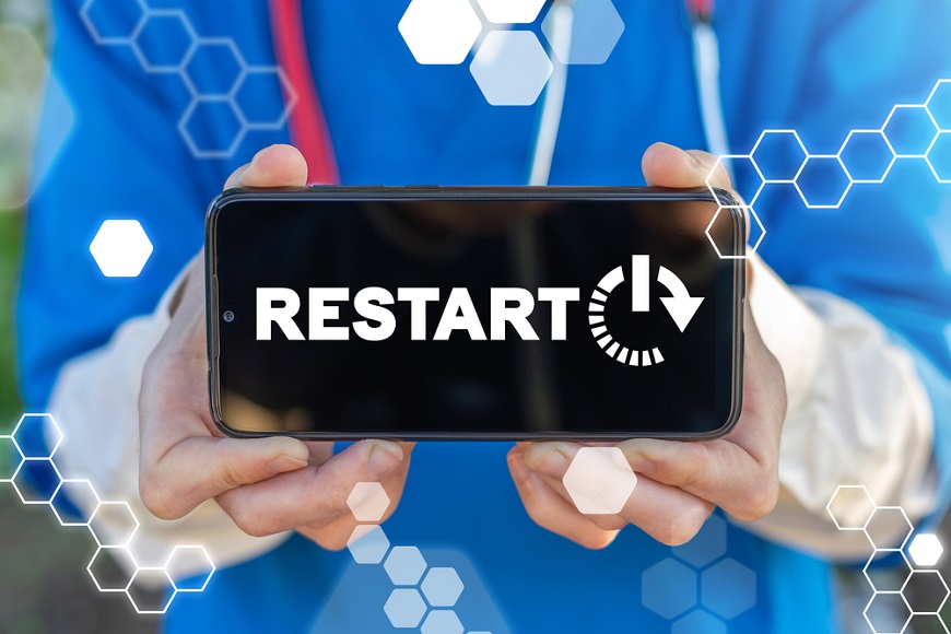 Ako reštartovať mobil? človek drží v rukách telefón s nápisom „RESTART“ na displeji