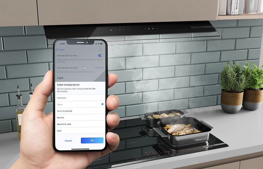 Prečo si vybrať vstavaný odsávač pár Bosch? Náhľad na mobilný telefón s aplikáciou Home Connect, v pozadí varná doska a odsávač pár