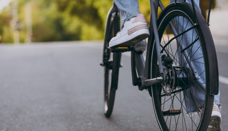 Ako vybrať elektrobicykel? žena v teniskách na elektrobicykli na ceste, detailný záber na bicykel