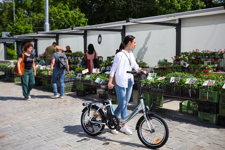 Ako vybrať elektrobicykel? žena so skladacím bicyklom po boku na trhu so zeleninou