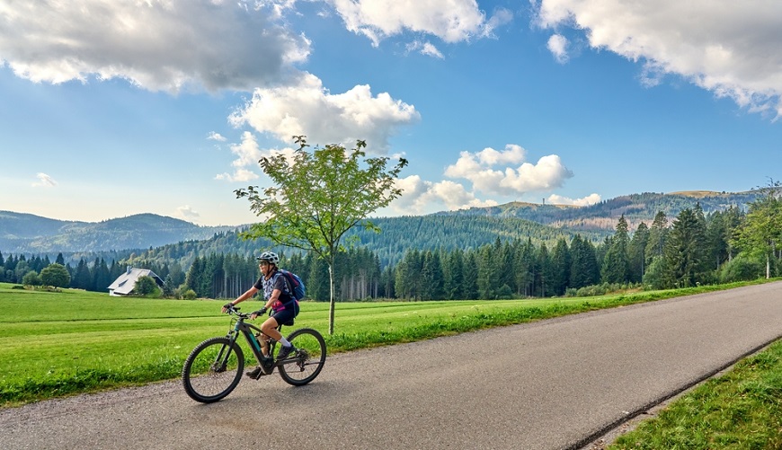 TOP dôvody, prečo si kúpiť elektrobicykel v NAY Scenéria, kde žena jazdí na elektrobicykli v horách.