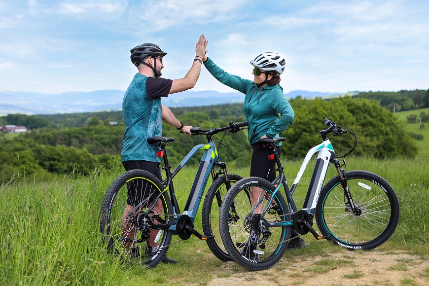 TOP dôvody, prečo si kúpiť elektrobicykel v NAY Muž a žena si dávajú high five po jazde na elektrobicykloch.