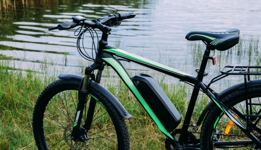 Elektrobicykel stojaci pri jazere v tráve.