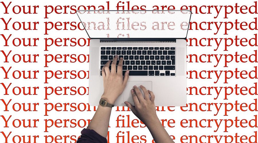 Ako zvládnuť bezpečnostné hrozby vo Windowse a Androide? osoba píše na laptope, detail, na pozadí je červený nápis Your personal files are encrypted