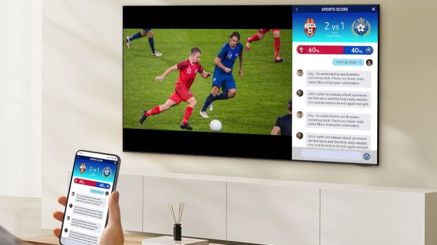 Ako ovládať televízor mobilom? Mobilný telefón, na ktorého displeji sú výsledky futbalového zápasu. V pozadí je televízor, na ktorom je vľavo futbalový zápas a vpravo to isté, čo na displeji mobilného telefónu.