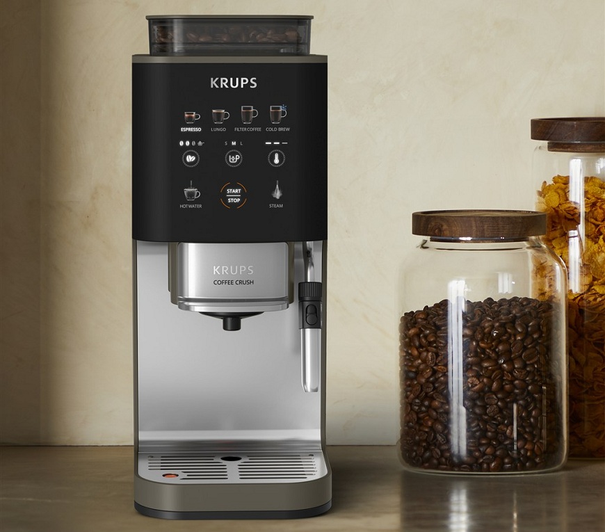  Kávovar Krups Coffee Crush na kuchynskej linke. Vedľa sklenená dóza so zrnkovou kávou.