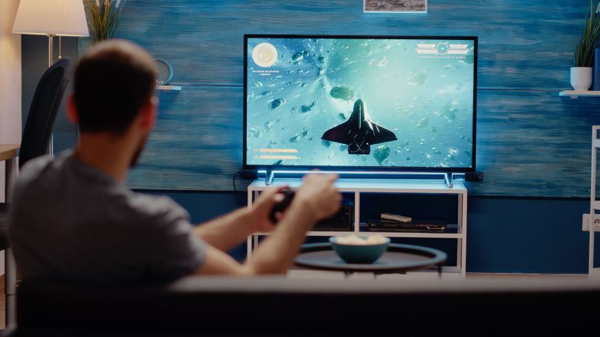 Najčastejšie televízne skratky a technológie Muž hrá hru na televízore.