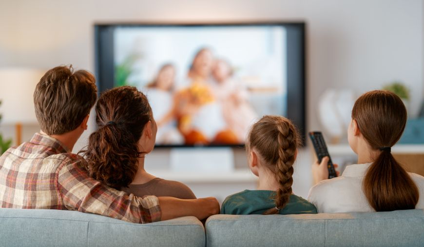 Najčastejšie televízne skratky a technológie Rodina sediaca na gauči sleduje televízor.
