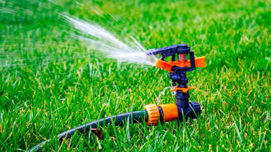 Ako založiť trávnik? detail na spustený závlahový sprinkler, ktorý postrekuje trávnik vodou