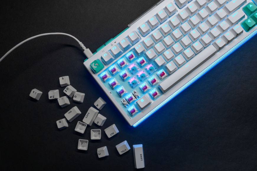 Biela klávesnica Logitech G512 X s odkrytou časťou spínačov, vedľa klávesnice leží hromádka keycapov