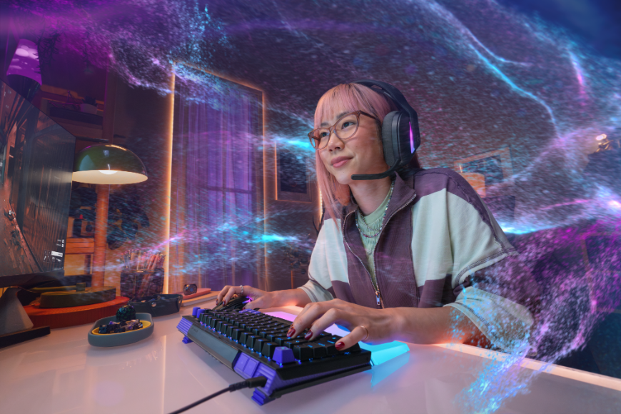 Žena hrá na klávesnici Logitech G512 X, okolo sú dúhové vlny zodpovedajúce farbám podsvietenia klávesnice