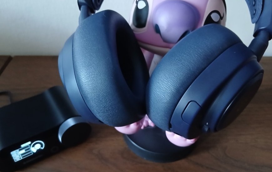 Recenzia: Arctis Nova Pro Omni – headset, ktorý vás prenesie priamo do hry Headset Arctis Nova Pro Omni je položený na stojane v tvare postavičky, vedľa leží zapnutý GameHub