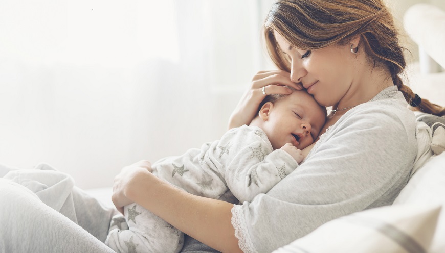 ETA Mimi: Tá najlepšia starostlivosť o vašich najmenších Matka leží v posteli a drží svoje bábätko na hrudi.