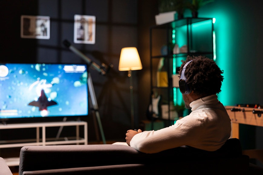 Xbox projekt Helix: Nová konzola chce zmeniť svet hrania Muž so slúchadlami na hlave hrá videohru na televízii pred sebou