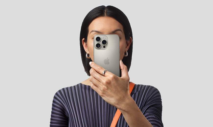 žena drží v ruke iPhone, ktorý prekrýva časť jej tváre, pohľad spredu
