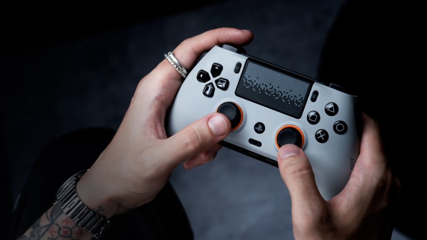 Ruky držia biely ovládač Scuf Omega s oranžovými detailmi