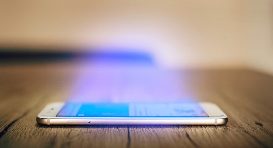 Ako vypnúť modré svetlo na iPhone iphone položený na stole, z ktorého vyžaruje modré svetlo