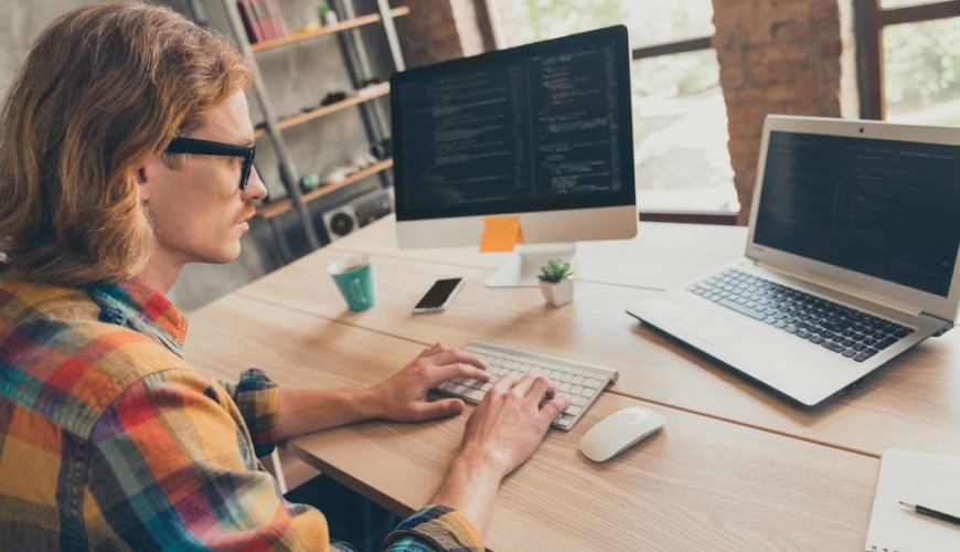 Muž pracujúci na počítači s externým monitorom a Linuxom.