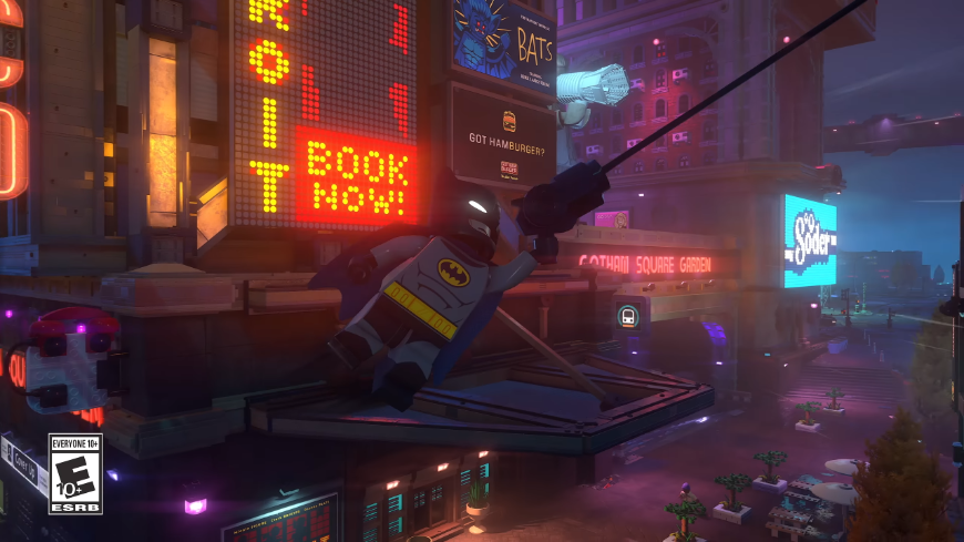 LEGO Batman: Legacy of the Dark Knight – Gotham z kociek ťa potrebuje! LEGO Batman sa hojdá na lane, na pozadí je mesto s neónovými nápismi