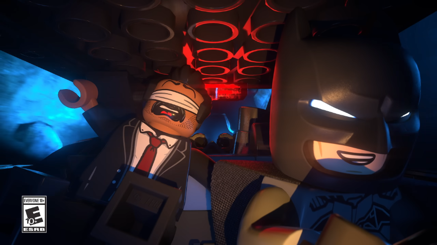 LEGO Batman: Legacy of the Dark Knight – Gotham z kociek ťa potrebuje! LEGO Batman riadi vozidlo a smeje sa, za ním sedí postava so zaviazanými očami
