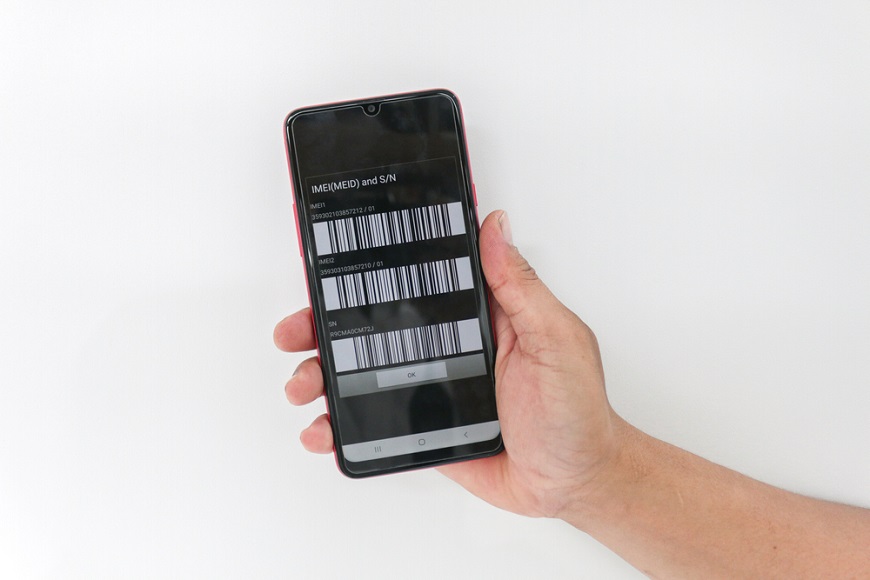 Ako nájsť telefón? Ruka držiaca mobilný telefón s čislom IMEI na displeji.