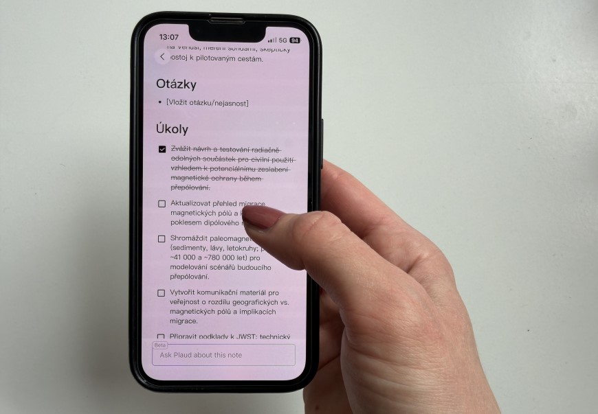 Ruka drží inteligentný diktafón so zobrazeným prepísaným textom