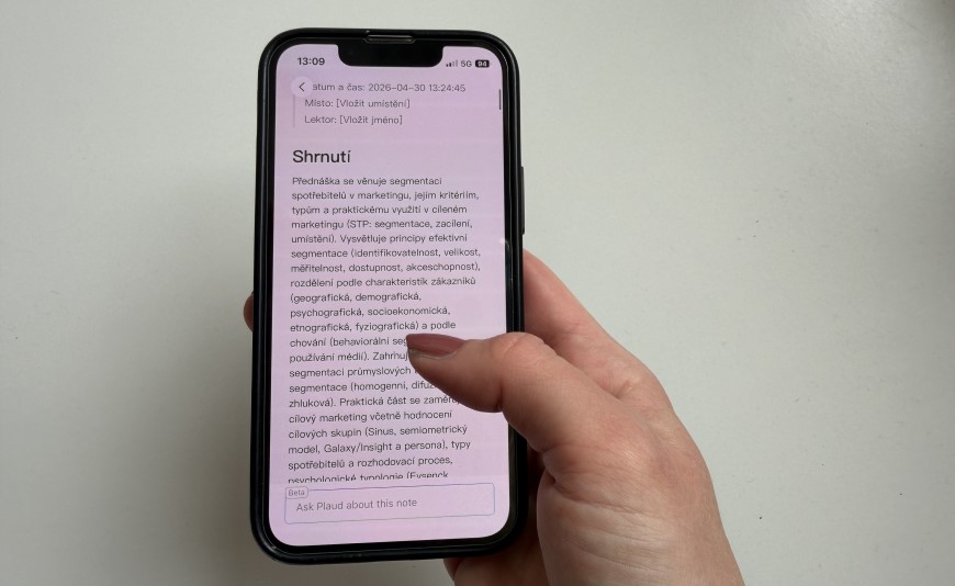 Ruka drží inteligentný diktafón so zobrazeným prepísaným textom.