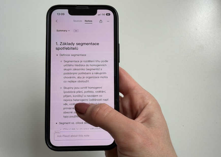 Ruka drží inteligentný diktafón so zobrazeným prepísaným textom.