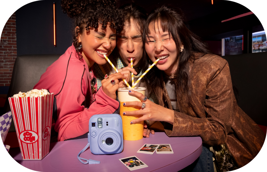 Tři kamarádi pózují pro Fujifilm Instax mini 13 a pijou colu a jí popcorn