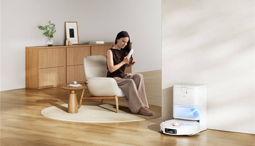 Žena si upravuje vlasy, zatiaľ čo robotický vysávač Xiaomi Robot Vacuum H50 Pro sa v dokovacej stanici dobíja