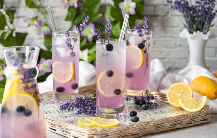 Ako pripraviť domáci sirup? Chuť leta ukrytá v každej kvapke Poháre naplnené levanduľovo-čučoriedkovým sirupom položené na pletenej tácke.