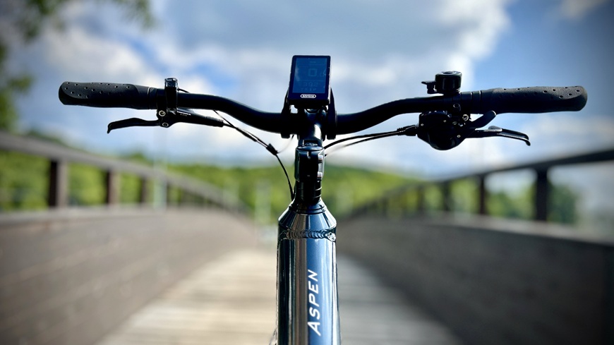 Recenzia: Elektrobicykel GoGEN Aspen MX 720 sa postará o to, aby vaše cyklistické túžby nič nebrzdilo Detail riadidiel a ovládače elektrobicykla GoGEN Aspen MX 720 uprostred drevenej lávky