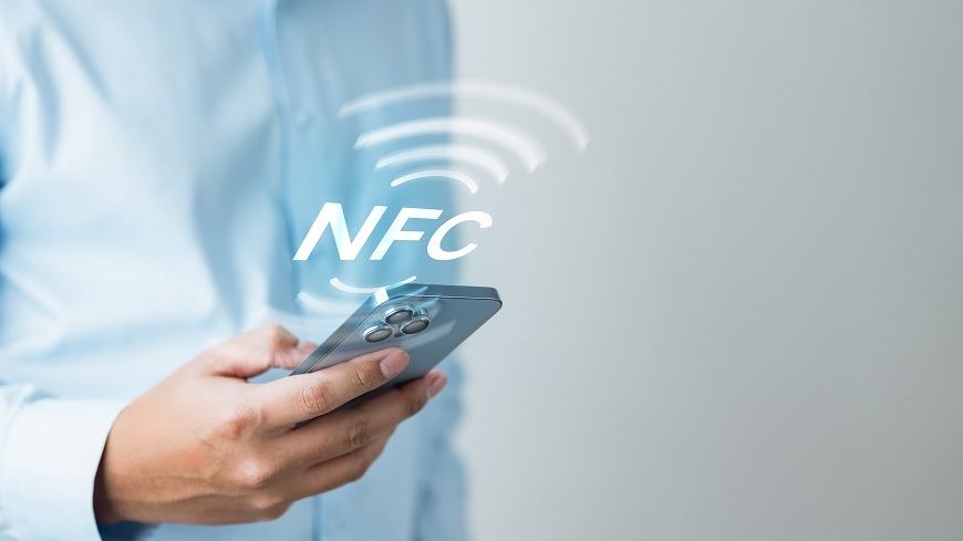 Ako platiť mobilným telefónom? Muž drží v ruke mobilný telefón, nad ktorým je symbol NFC.
