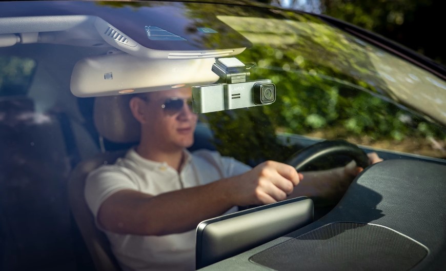 Muž sedí za volantom a za spätným zrkadlom má umiestnenú autokameru.